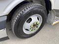 A close-up of a 2020 Chevrolet Express wheel featuring a tire with a tread pattern and bright green lug nut covers