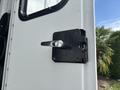 A metallic door handle attached to a black latch on a white vehicle door