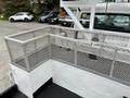 A 2013 Freightliner 114SD heavily loaded with a metal mesh guardrail surrounding a flatbed area on the truck