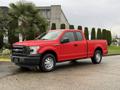 Red 2015 Ford F-150 pickup truck with a black grille and a single cab parked on a driveway