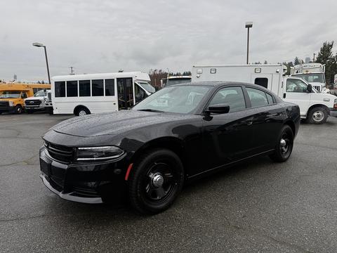 A black 2017 Dodge Charger with a sleek design and black rims parked at a lot with other vehicles in the background.