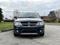 A dark blue 2013 Dodge Journey parked with a front view showcasing its distinctive grille headlights and bumper design