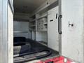 A 2007 GMC C4500 TopKick truck with an open cargo area featuring empty shelves and a pair of tires on the floor