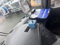 A blue control switch is positioned on a textured black surface inside a vehicle cabin