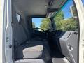 Interior view of a 2022 Isuzu NQR showing the driver's seat and dashboard area with gray fabric seats and controls