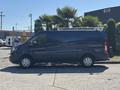 A blue 2016 Ford Transit 150 van parked with a ladder rack on the roof and side doors open