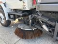 A 2012 International DuraStar 4300 equipped with a large circular street sweeper brush attached to its front