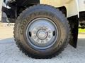 Close-up of a Goodyear tire mounted on a 2009 International 3000 CE bus featuring a silver rim and multiple lug nuts spotlighted by the sunlight