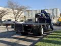 A 2015 Hino 358 flatbed truck with a crane mounted on the back and rear-facing lights visible