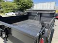 A 2019 Ford F-550 truck bed with a flatbed design featuring a dark surface and a tethered cover at the rear