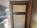 A vintage 1976 GMC Motorhome interior featuring a beige and brown refrigerator with a textured finish and a metal handle