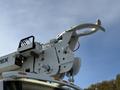 A white 2011 International 7500 truck equipped with a hydraulic lift arm and a hook attachment for lifting objects