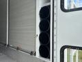 A close-up view of the side of a 1994 GMC Vandura 3500 showing cylindrical black storage compartments attached to the vehicle's exterior