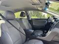 Interior of a 2014 Hyundai Sonata featuring gray fabric seats and a black dashboard with controls and a console between the front seats