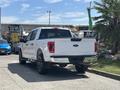 A white 2021 Ford F-150 pickup truck viewed from the rear with black wheels and a chrome rear bumper