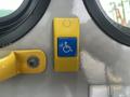 A yellow and blue handicap accessibility button mounted on a vehicle door