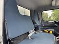 A 2015 Mitsubishi Fuso FE160 with a blue fabric bench seat and gray upholstery in the cabin