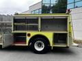 A yellow 1995 Freightliner FLL086 fire truck with open compartments displaying equipment and storage areas
