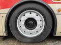 A close-up view of the wheel of a 2016 Grande West Vicinity bus featuring a black tire and a silver wheel with multiple bolt holes