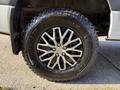 A close-up of a black alloy wheel with a multi-spoke design mounted on a large off-road tire with rugged tread patterns