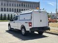 A white 2019 Ford F-150 pickup truck with a fitted utility cap and ladder rack on the bed visible from the rear angle