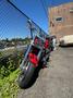 A 2007 Honda VTX1800F3 motorcycle in red and chrome with a distinctive front headlight and prominent tires leaning against a fence
