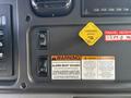 Dashboard controls of a 2019 Freightliner M2 106 featuring buttons for regeneration alarm and a parking brake warning with labels in English and Spanish