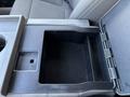 A black console in the front cabin of a 2017 Ford F-550 with an open compartment and space for storage