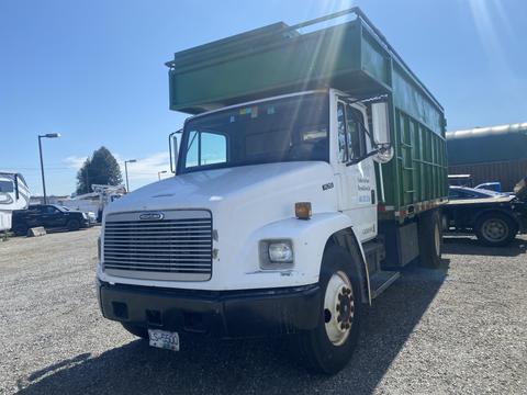 A 1997 Freightliner FL70 truck with a white cab and green dump bed parked in a lot