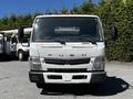 A 2013 Mitsubishi Fuso FE160 with a white exterior facing forward displaying the brand name Fuso in large letters on the grille and equipped with side mirrors and orange roof lights
