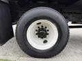 A close-up of a large white and black tire mounted on a truck wheel with multiple lug nuts visible in the center
