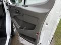 A gray interior door panel of a 2023 Ford Transit featuring a handle and control buttons