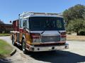 A 2004 American LaFrance Eagle fire truck with a red and gold color scheme features a shiny chrome front bumper and multiple lights on the roof