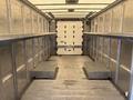 Interior of a 2018 Ford Econoline cargo van showing metal walls and wooden floor with two built-in shelves on either side