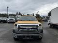 A yellow 2014 Ford F-150 truck is parked in the foreground with a large grille and a bold Ford emblem on the front