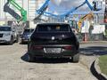 A black 2023 Fisker Ocean electric SUV is parked with its rear visible showcasing the brand logo and model name in the center of the tailgate