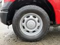 A close-up of a silver wheel rim mounted on a large all-terrain tire belonging to a red 2015 Ford F-150