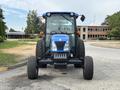 A blue and black 2009 New Holland T4020 tractor facing forward with large tires and an enclosed cabin