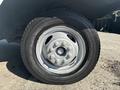 Close-up of a silver wheel and tire from a 2012 Ford E-450 showing five lug nuts and a rugged tread pattern