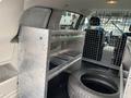 Interior of a 2014 RAM Cargo Van featuring metal shelving units and a tire on the floor
