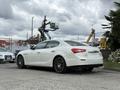 A white 2016 Maserati Ghibli with a sleek design and sport wheels parked on a street