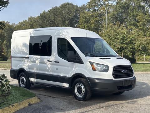 A 2016 Ford Transit 150 van in white with a black front grille and wheels parked on a driveway