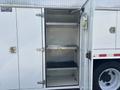 A 2006 International 4300 service truck with an open compartment featuring three metal shelves and a circular light fixture mounted on the interior wall