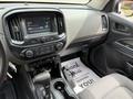 The interior of a 2017 Chevrolet Colorado featuring a dashboard with a touchscreen display and controls for audio and climate settings along with a gear shifter and cup holders