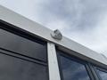 A close-up view of a 2020 Chevrolet Express showing a mounted device on the upper corner of a window with a sleek white exterior and large black-tinted windows