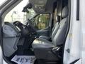 Interior of a 2016 Ford Transit 150 featuring gray leather front seats and a minimalist dashboard with controls and storage compartments