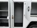 A 2020 Ford F-550 service vehicle with an open side compartment showing empty shelves and a large space for storage