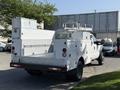 A white 2015 Ford F-550 utility truck with a flatbed and tool compartments mounted on the back