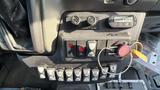 Control panel of a 2021 Ford Transit featuring various switches and buttons for lights and other functions along with a key ignition and a fire safety tag