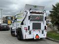 A 2012 Global M4 street sweeper with a white exterior and green accents, featuring a large rear hopper and a grid-patterned panel on the back